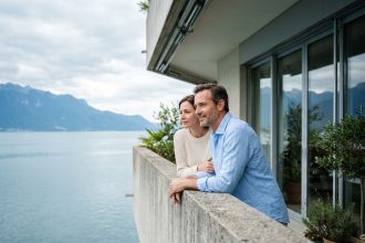 Couple sur le balcon d'un appartement neuf à Thonon-les-Bains avec vue panoramique sur le lac Léman et les Alpes
